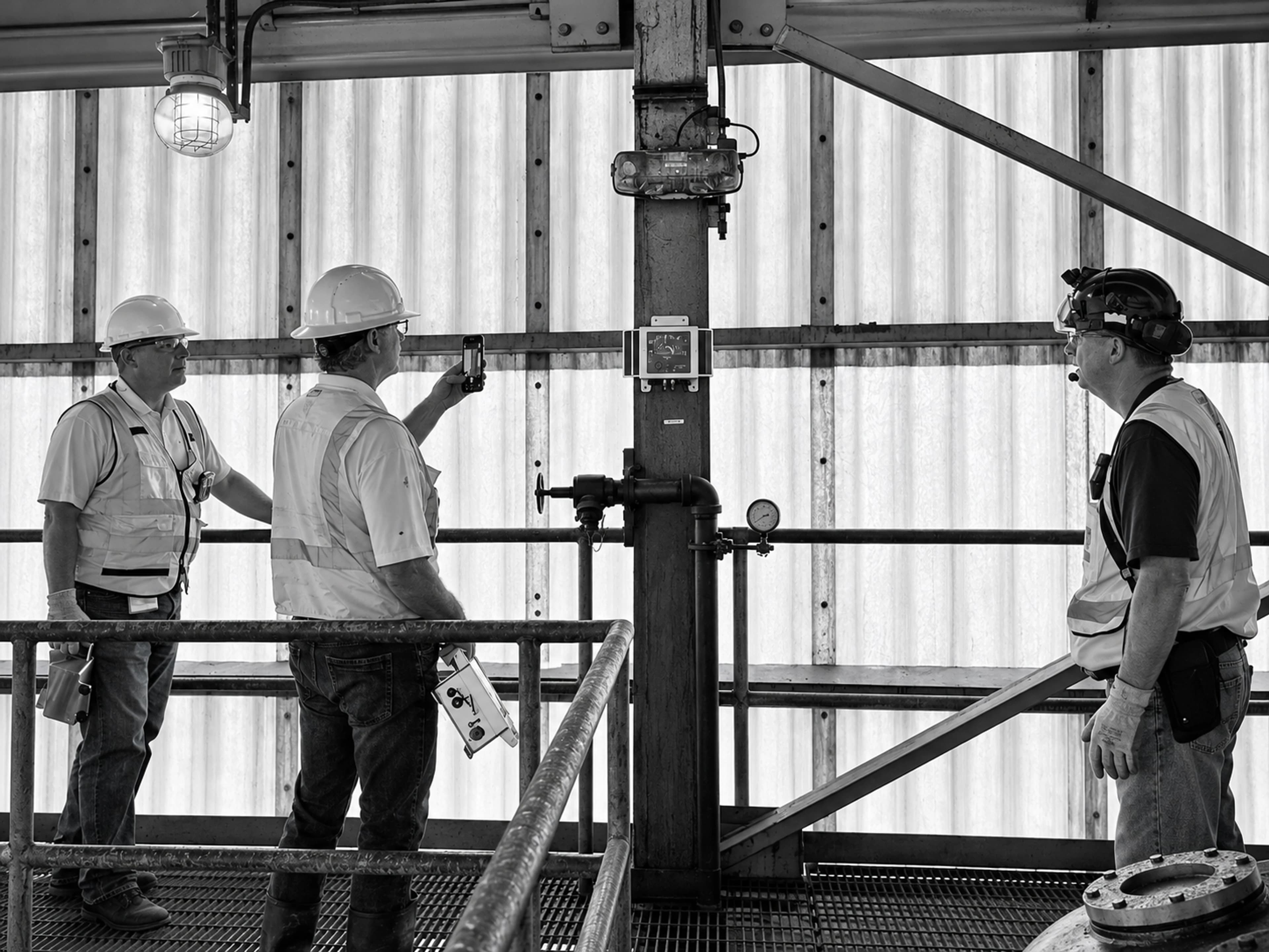 Structural engineers inspect monitoring equipment mounted on a steel column inside a building